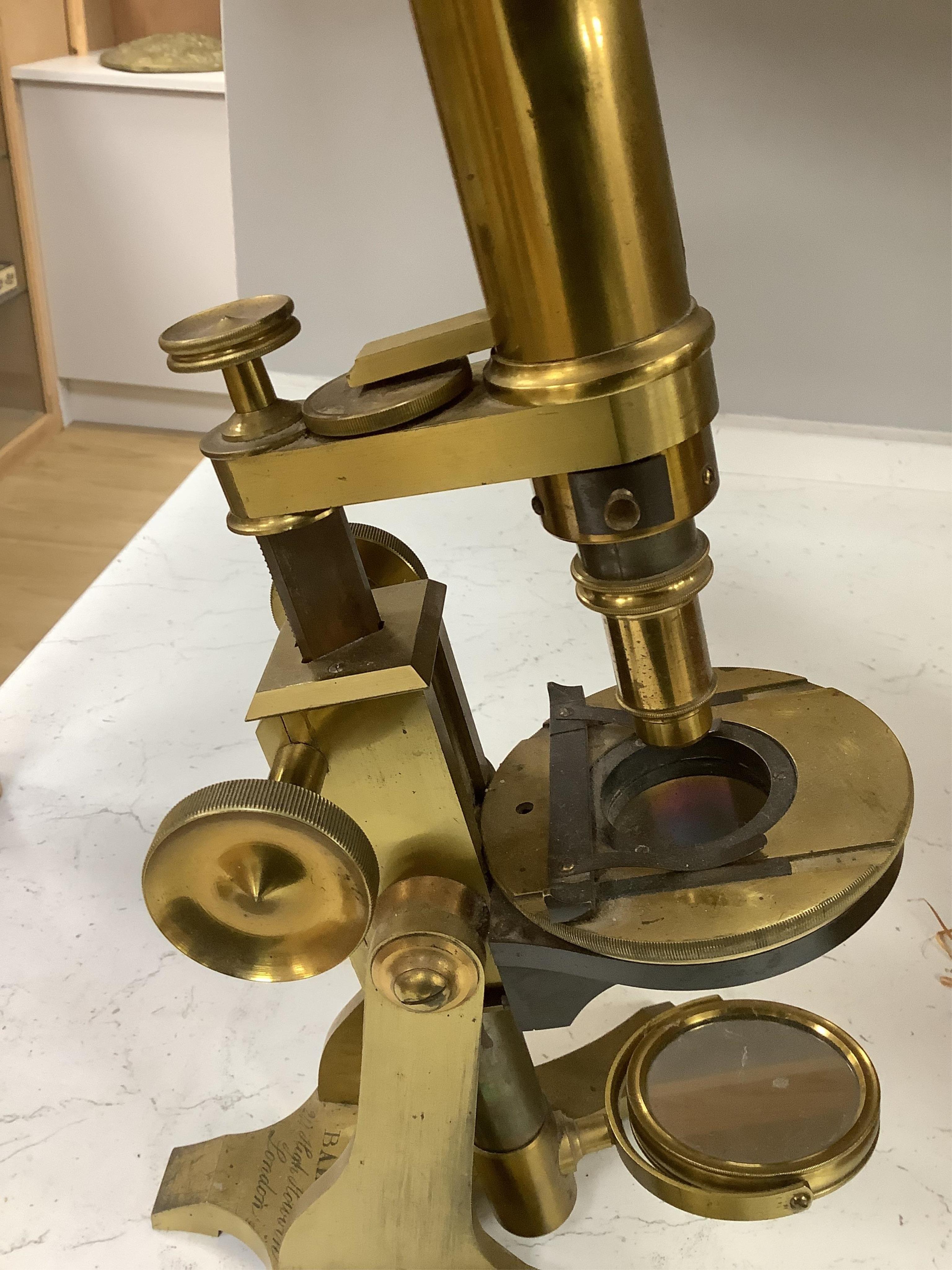 A 19th century brass compound binocular microscope, engraved to the base Baker, 244 High Holborn, London, with four brass cased objective lenses, 47cm high. Condition - fair to good